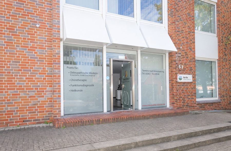 Klinkerfassade des Praxisgebäudes mit gläserner Eingangstür und Revita-Schild